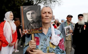 A woman holds a photograph of a war veteran