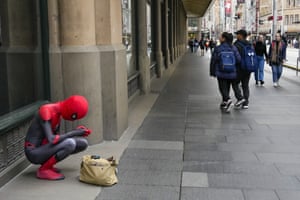 Sydney, Australia. A man dressed in a Spider-Man suit checks his phone