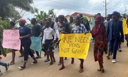 Protesters march with signs saying ‘we need pens, not guns’