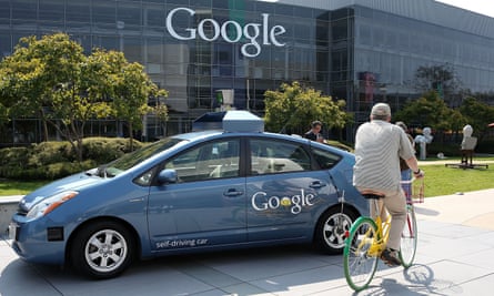 A bicyclist rides by a self-driving car being developed at the Google headquarters in California in 2012.