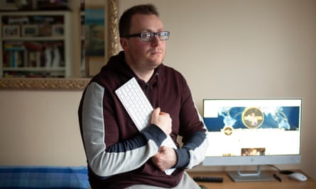 David Clews clutching a keyboard in front of a desktop screen