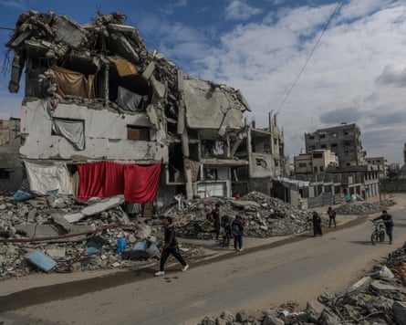 Palestinians walk past destroyed houses in Gaza.