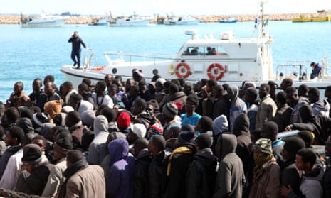 Migrants wait to disembark from a tug boat after being rescued in the Mediterranean. An Italian government official says four smugglers brandishing Kalashnikovs threatened an Italian Coast Guard motorboat that had just rescued migrants off the coast of Libya.