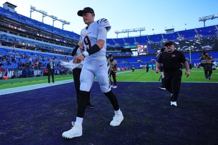 Joe Burrow jogs across the field in a white away uniform after a game