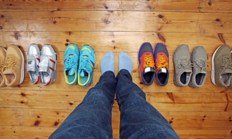 Person wearing socks stands next to row of shoes.