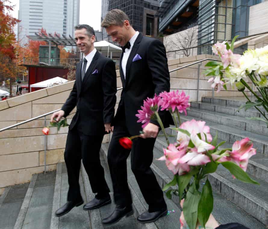 Dan Savage, left, and his husband Terry Miller walk past well-wishers after wedding at Seattle City Hall, becoming among the first gay couples to legally marry in the state, 9 December 2012.