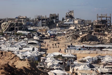A view of the camp with destroyed buildings seen in the background.