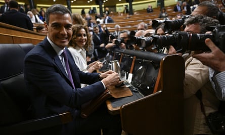 A smiling Sánchez surrounded by fellow politicians and photographers