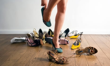 Woman’s legs surrounded by shoes.