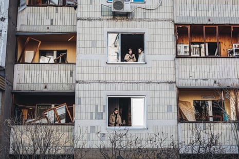 Residents look out of a shell-damaged house in Kyiv