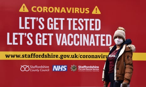 A woman in front of a sign reading ‘Let’s get tested – let’s get vaccinated’