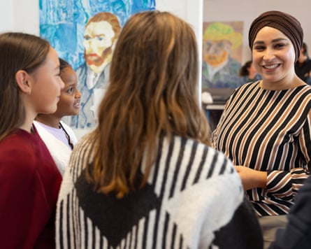 Hafsa El-Bazioui standing in a room with children in front of her, with paintings on the wall