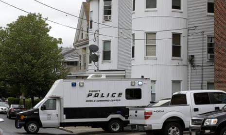 Police vehicles sit in front of a multi-storied home on Tuesday in Everett, Massachusetts, being searched by authorities in connection with a man shot and killed earlier in the day in Boston.