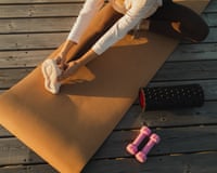 Female athlete stretching on yoga mat before outdoors workout with dumbbells and foam rolerSports concept. Top view of sportsperson with exercise equipment. Female mental health and wellbeing, sportive hobby and physical activity. Background with unrecognizable woman and room for copy space or sign.