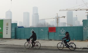 Cyclists ride past an entrance at a closed construction site on the second day of a ‘red alert’ for pollution in Beijing on 20 December.