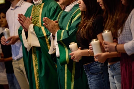 two priests and four students holding candles