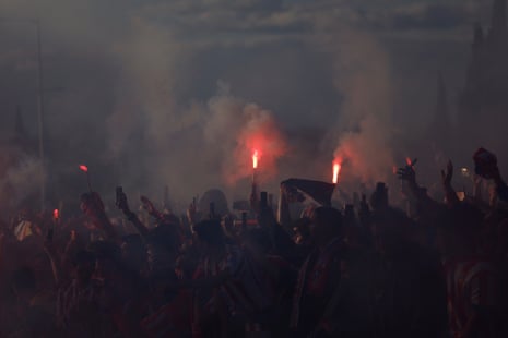 Atletico Madrid’s supporters hold flares and mobile phones as they wait for the arrival of their team’s bus.