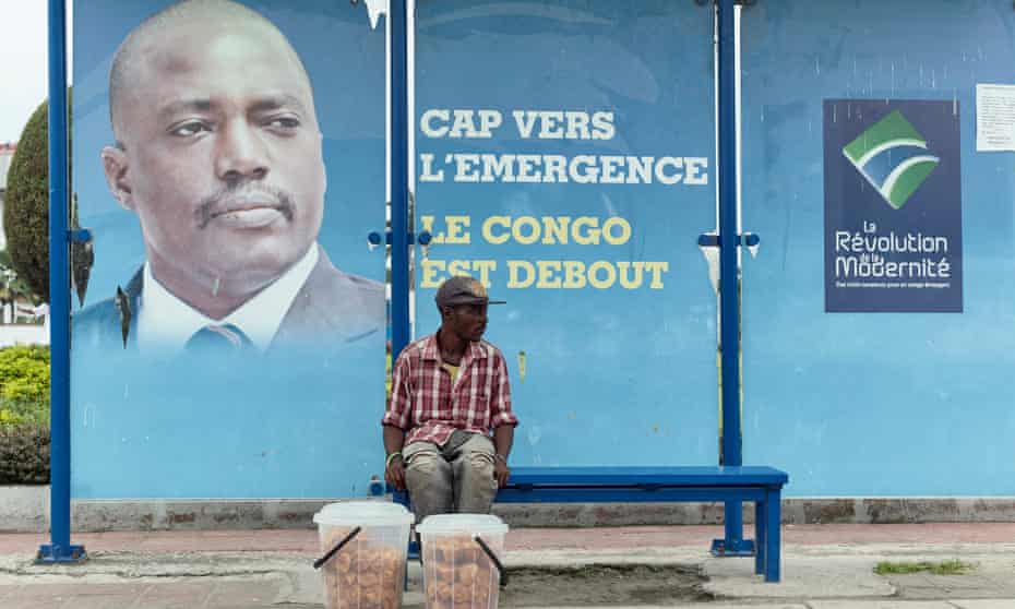 A vendor at a bus stand in Kinshasa in front of a picture of President Joseph Kabila.