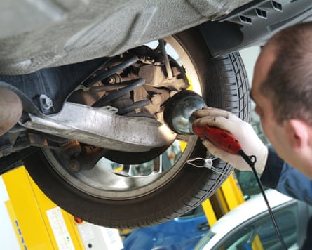 Garage mechanic checking underneath of car