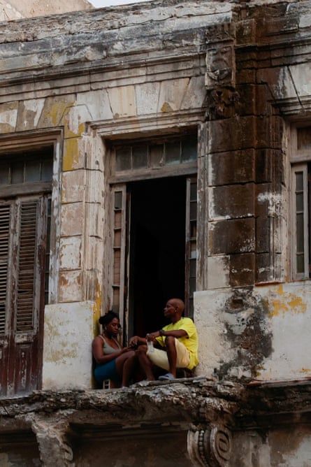 People sit on what is left of the balcony of their home during a blackout.