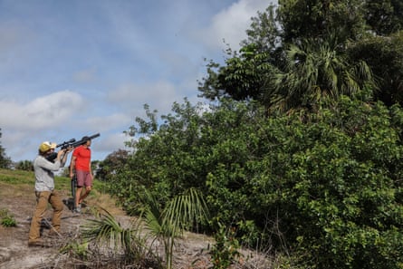 a man standing next to another man with a rifle