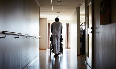 A nurse pushes a man in a wheelchair