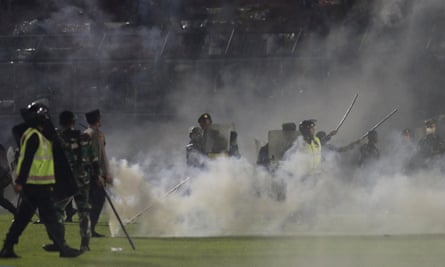 Police and soldiers amid tear gas smoke at the soccer match at Kanjuruhan stadium on 1 October 2022