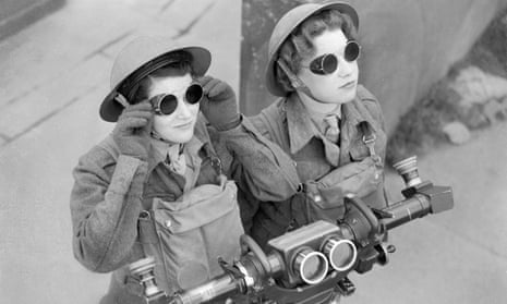 ATS spotters, wearing sunglasses, watch for any sign of hostile aircraft at a London anti-aircraft battery. In front of them is a range-finder. 