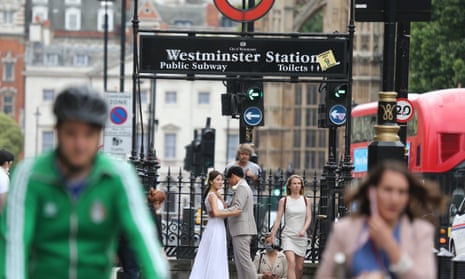 A couple pose for wedding photos outside Westminster Station in London as people pass by.