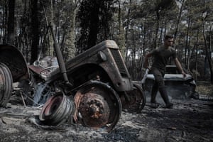 A French hunter walks past a burnt car during an operation to set up water points for wild animals in a forest ravaged by a wildfire near Pyla sur Mer in Gironde