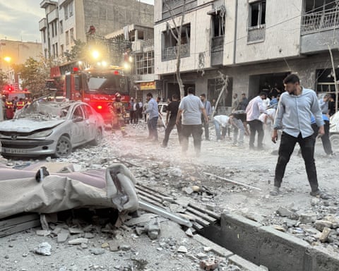 People gather outside an area hit by an Israeli strike in Tehran on 13 June.