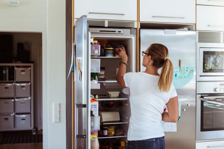 Rear view of a woman looking into refrigerator while standing in kitchen