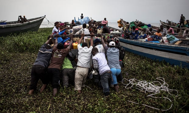 People pushing boat out at Lake Albert, DRC.