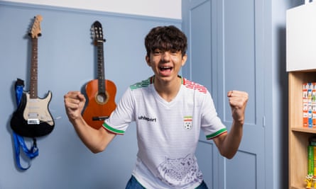 England’s united nations of football: 32 teams, one World Cup – and a lot of excited kids | World Cup 2022 19 Tinoosh Simpkins clenching his fists in excitement while wearing a white Iran shirt and standing in a room with two guitars on the wall behind him