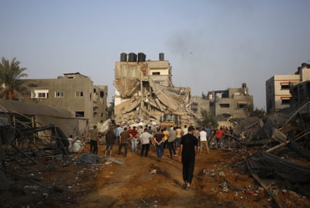 أشخاص يقومون بعملية بحث وإنقاذ للفلسطينيين العالقين تحت أنقاض مبنى مدمر، في دير البلح في 24 أكتوبر 2023.