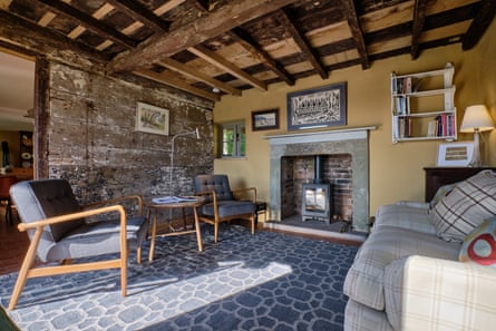 A beamed living room with a woodburner and paintings on the walls
