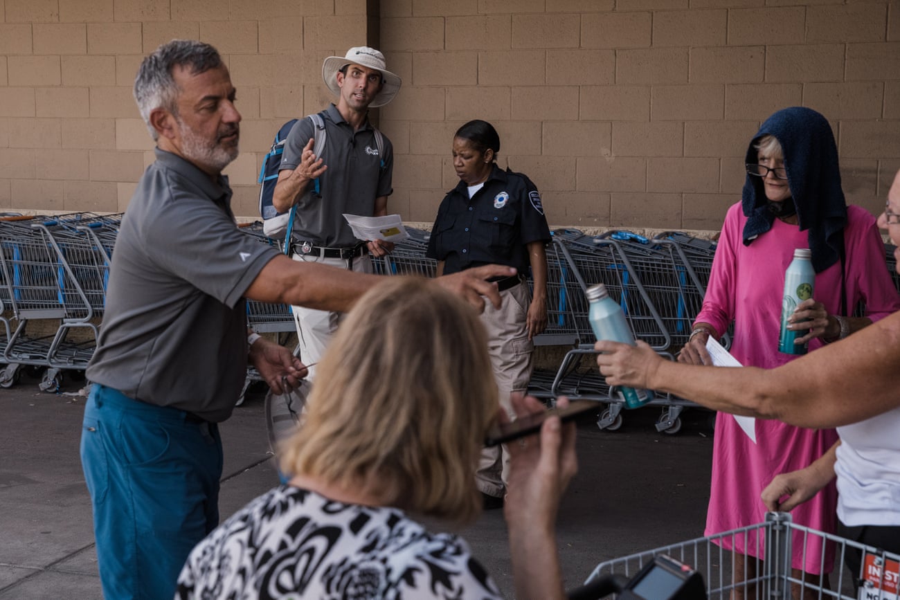 Hondula talks with a security guard at a store while volunteer Ray Miller distributes water during a shift of outreach.