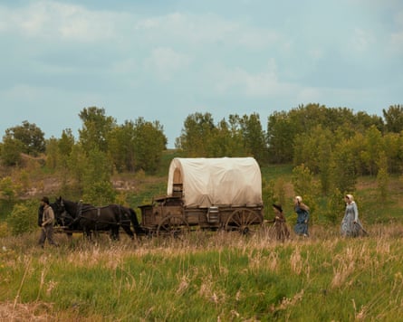 People stepping alongside a horse-drawn barrel-top trailer