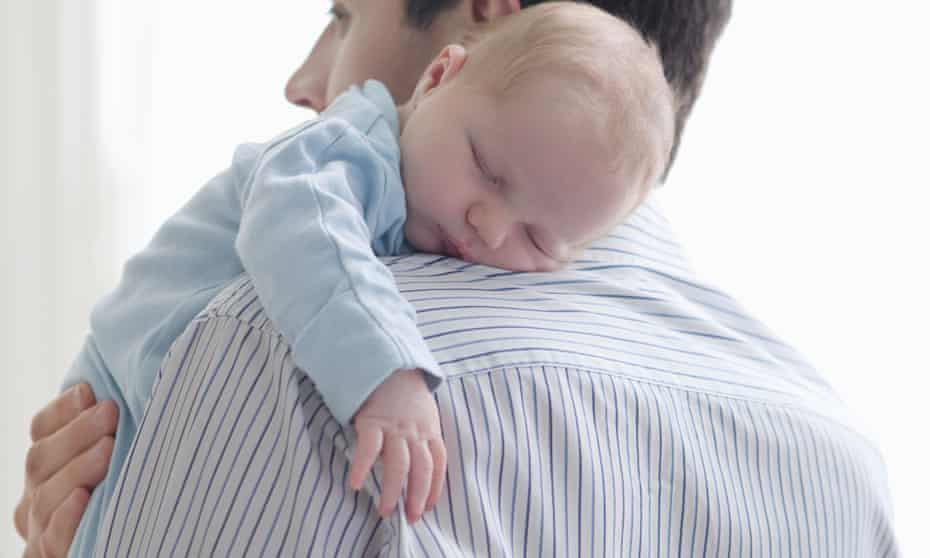 Father holds newborn baby on shoulder