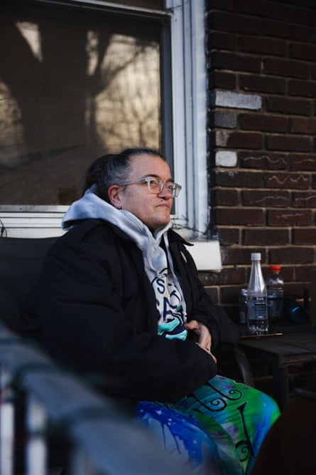 A middle-aged woman sits outside a house.