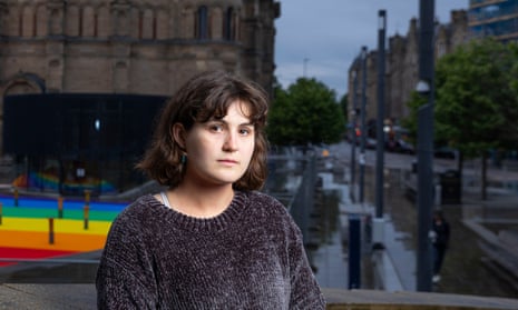 Isabelle Murray, with shoulder-length hair, leans against a concrete wall, hands folded, in front of the University of Edinburgh’s McEwan Hall