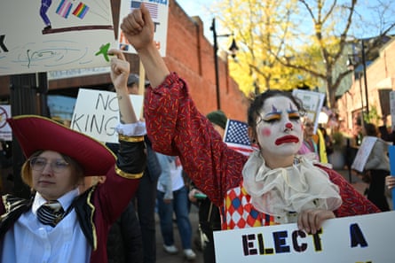a person dressed as a clown with a fist in the air attends a protest