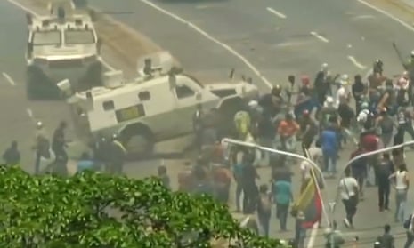 A National Guard armoured vehicle drives into protestors on a large roadway outside La Carlota airbase in Venezuela.