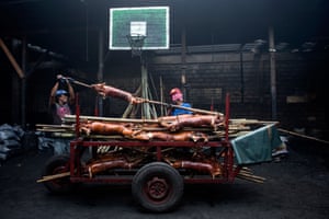 Workers carrying a roasted pig to be sold on the streets of Manila. Also known as lechón, roasted pig is a regular dish at Philippine festivities, especially during Christmas and new year