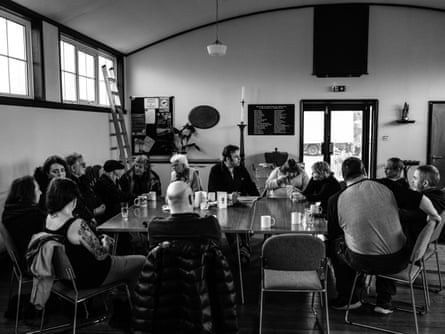 People sit around a large square table in a community club