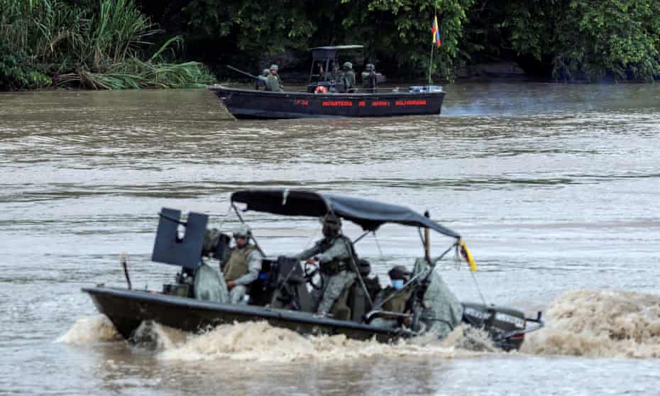 A Colombian navy boat patrols the Arauca river while a Venezuelan navy boat remains anchored on the border between their two countries as seen from Arauquita, Colombia.
