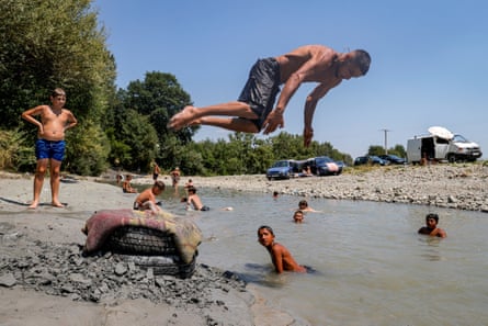 people swim in a river as one person jumps in