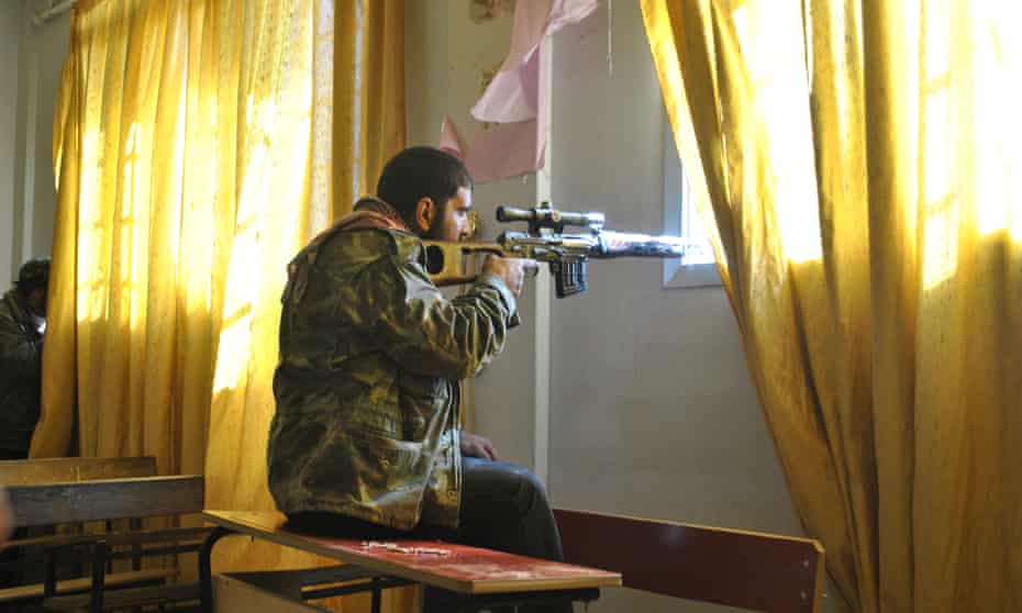 A Syrian rebel aims his rifle inside a classroom at a school in Deir Baalbeh neighbourhood in Homs province in February 2012