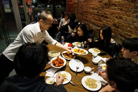 A man serves food to a table of restaurant patrons.