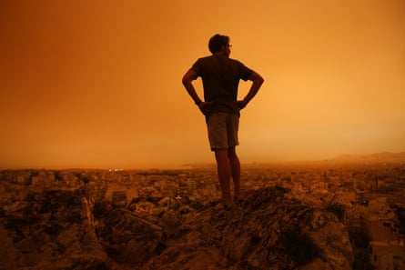 A man looks out at the orange haze covering Athens